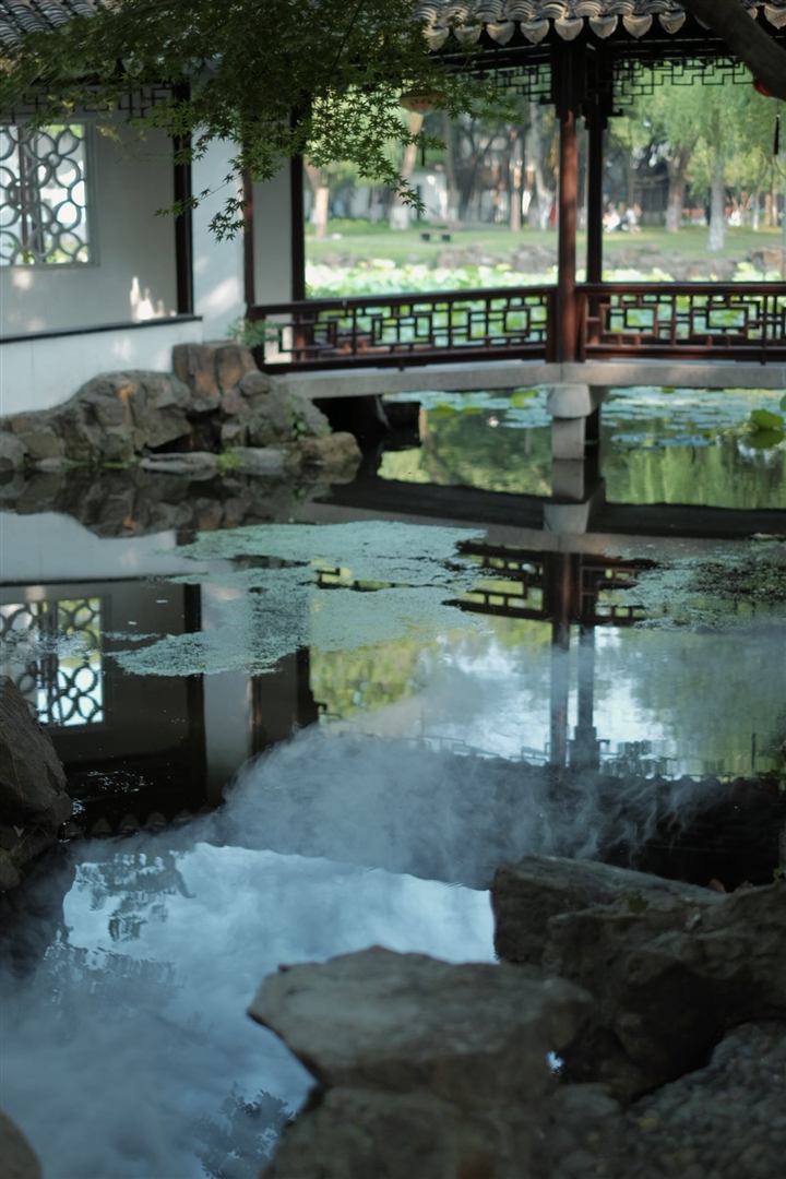 A covered garden pavilion beside a pond.