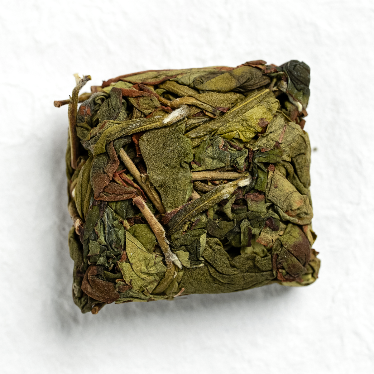 Pressed square cake of Zhangping Shui Xian oolong tea on neutral white paper