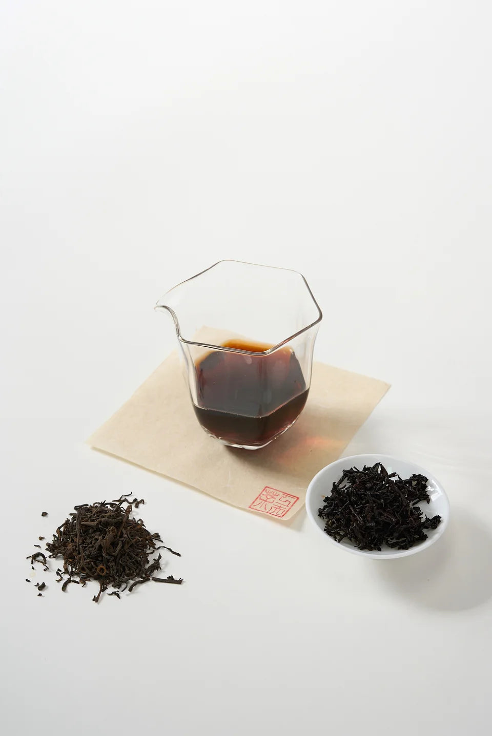 Loose dark tea beside a deep brown infusion and opened leaves.