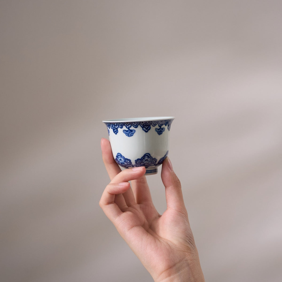 Baoxiang Floral Blue-and-White Porcelain Tea Cup held in hand for scale
