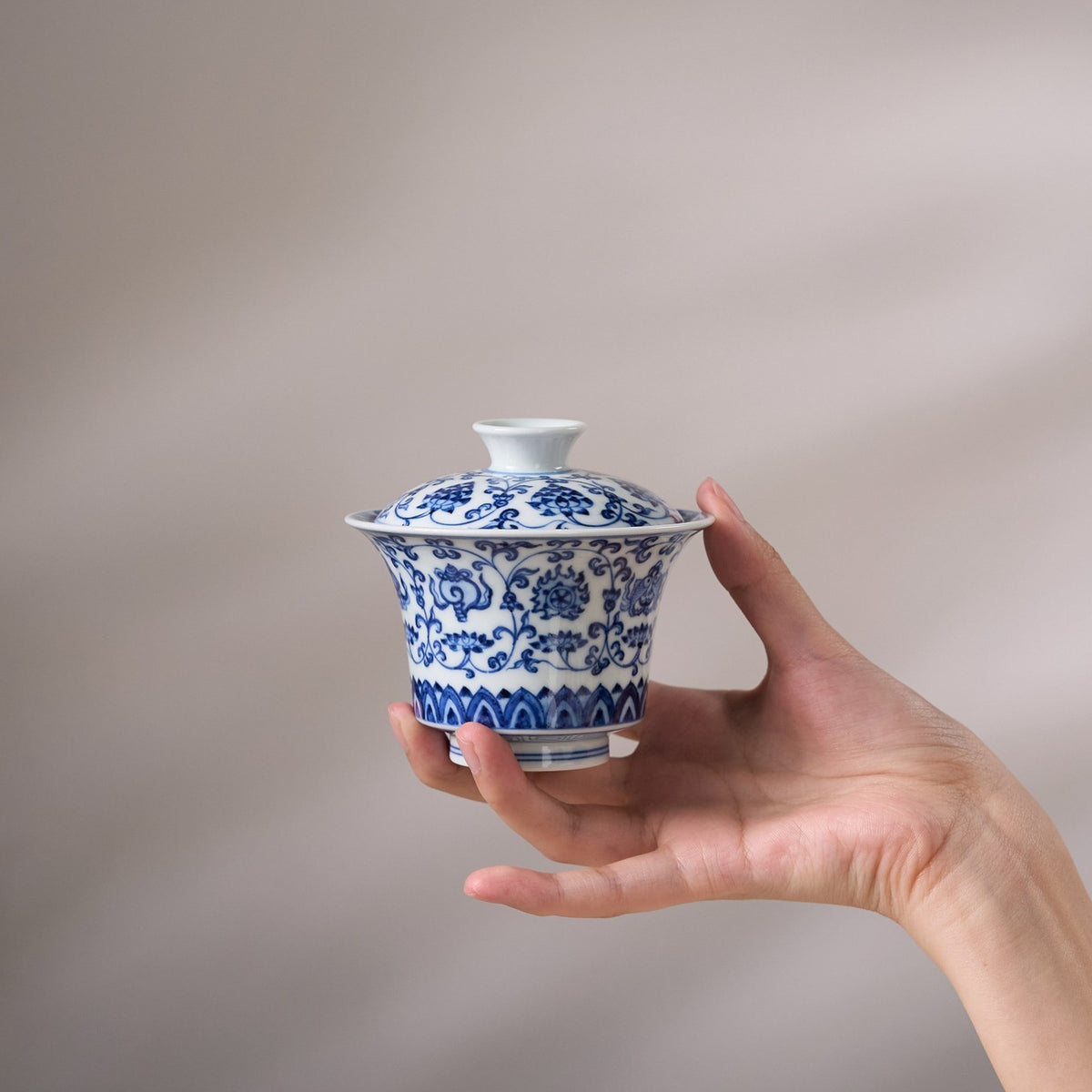 Eight Treasures & Scrolling Lotus Porcelain Gaiwan held in hand for scale