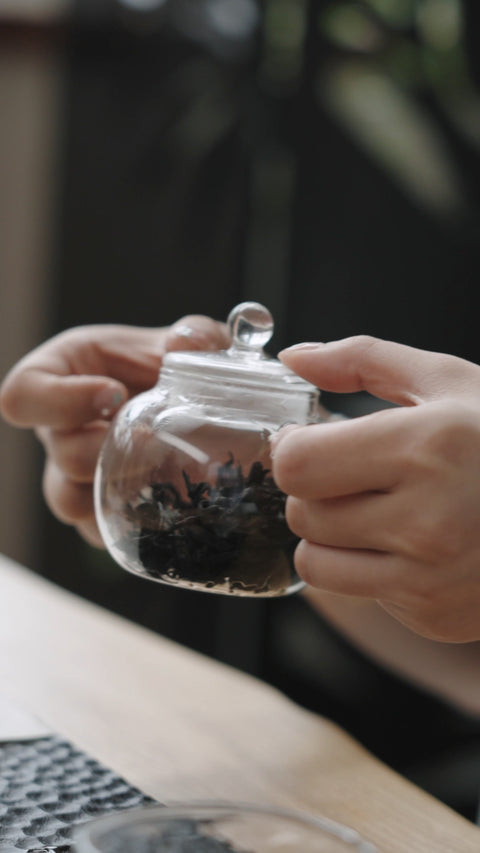 Dry tea leaves inside a glass teapot before adding water