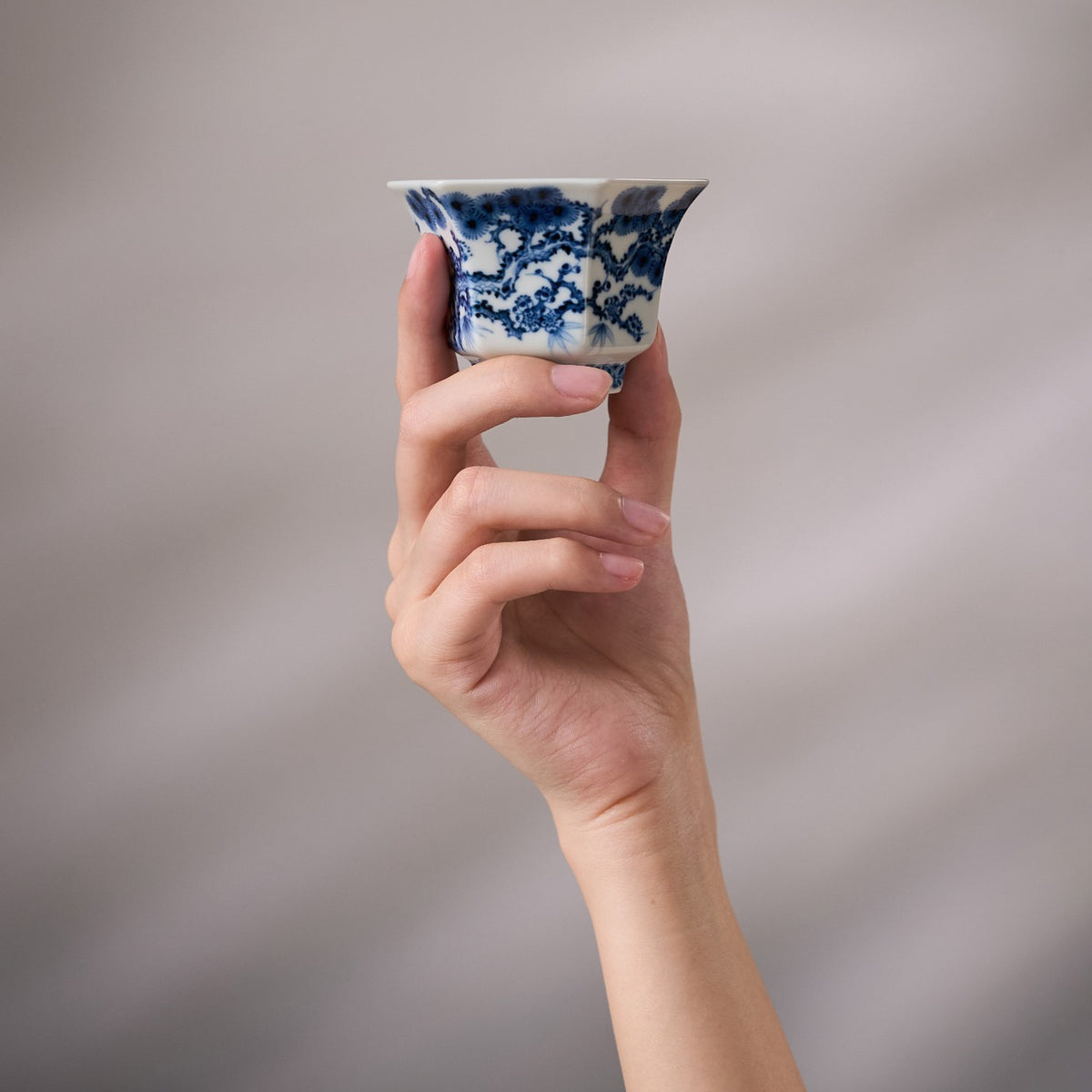 Three Friends of Winter Hand-Painted Octagonal Tasting Cup held in hand for scale