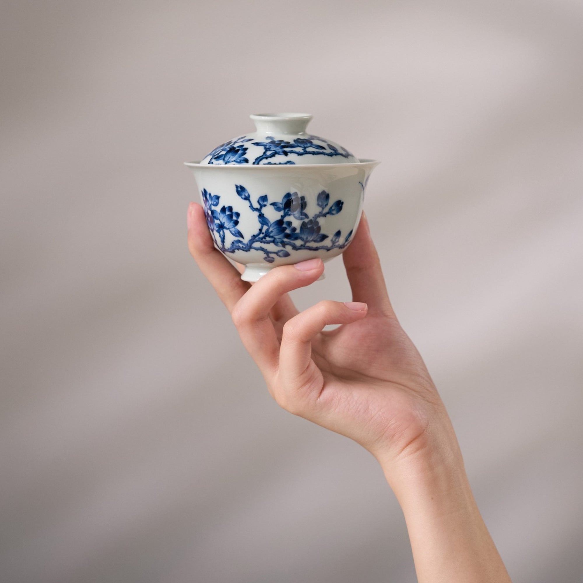 White Magnolia Blue-and-White Porcelain Gaiwan held in hand for scale