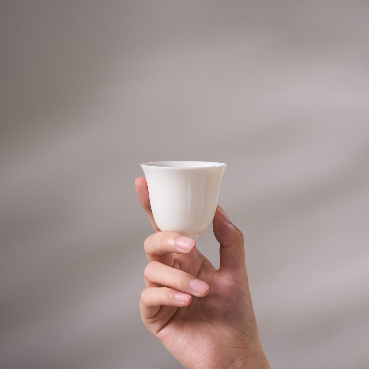 White Porcelain Small Tea Cup held in hand for scale