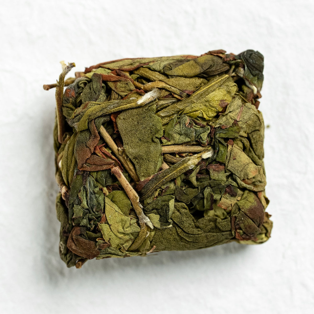 A pressed square of Zhangping Shui Xian dry tea on a light surface