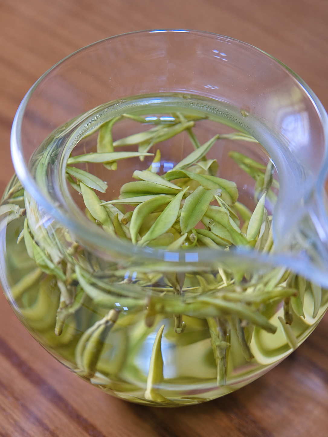 Tea leaves steeping in a clear glass cup