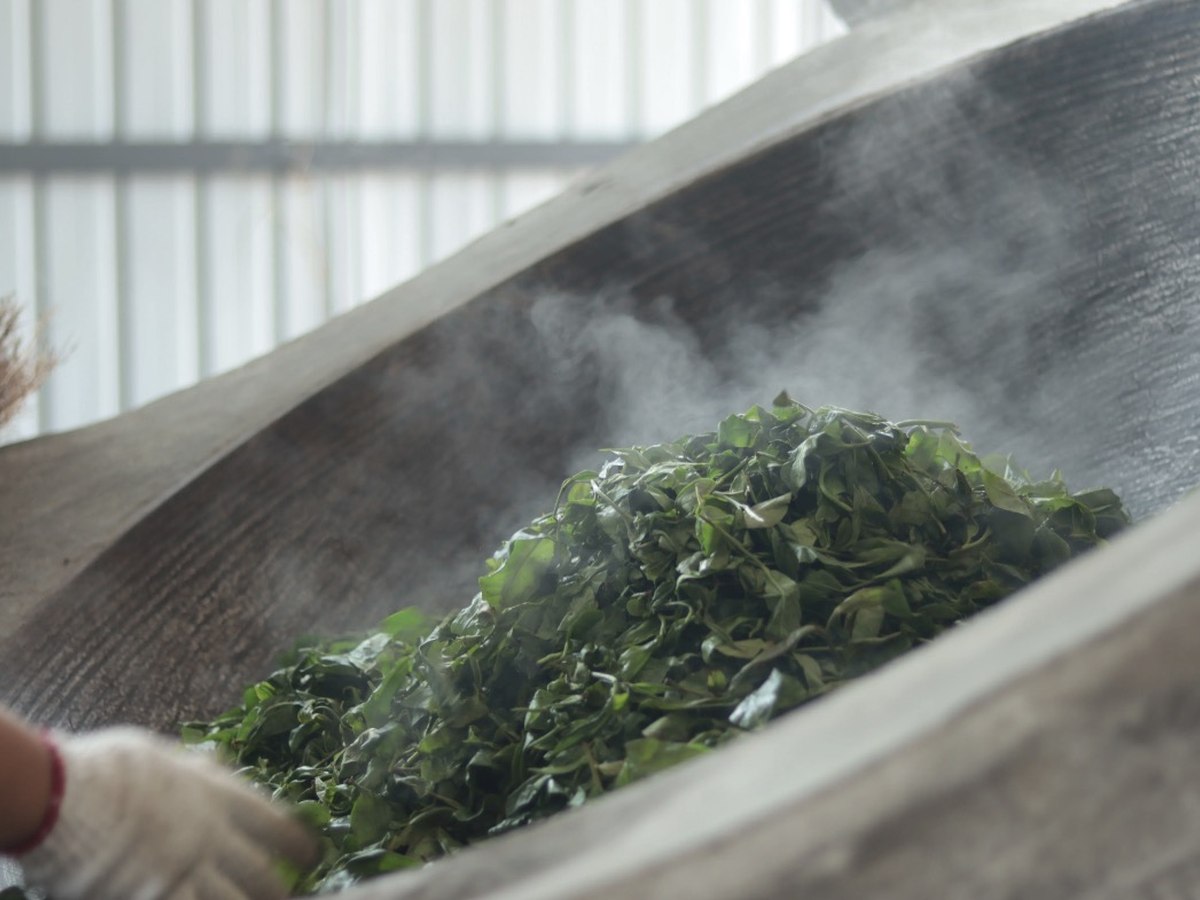 Hands moving tea leaves through a heated pan