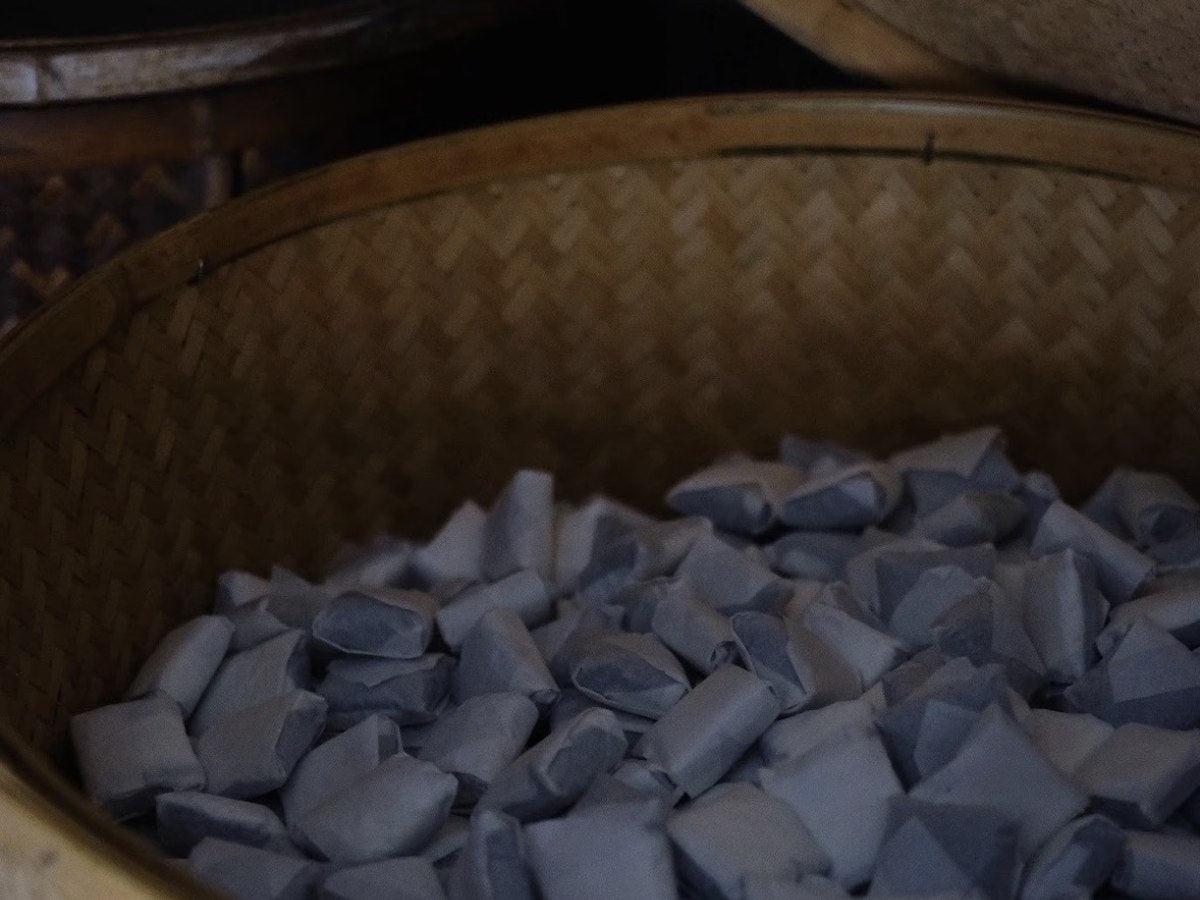 Paper-wrapped tea squares in a bamboo drying basket