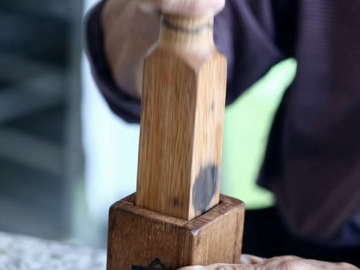 Hands pressing tea in a wooden mold