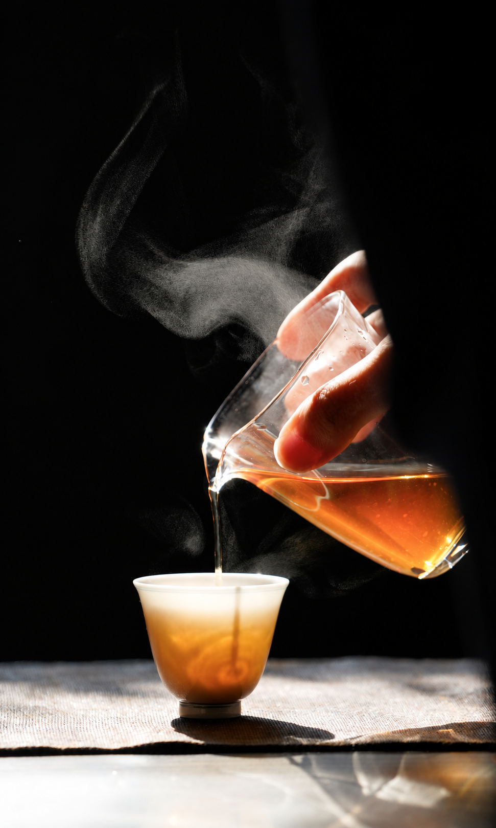 Tea being poured from a glass pitcher into a small ceramic cup