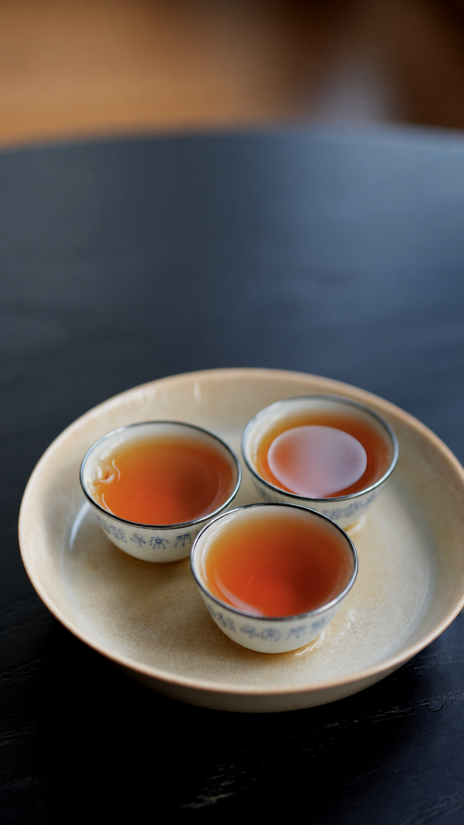 Three cups of amber tea on a pale plate