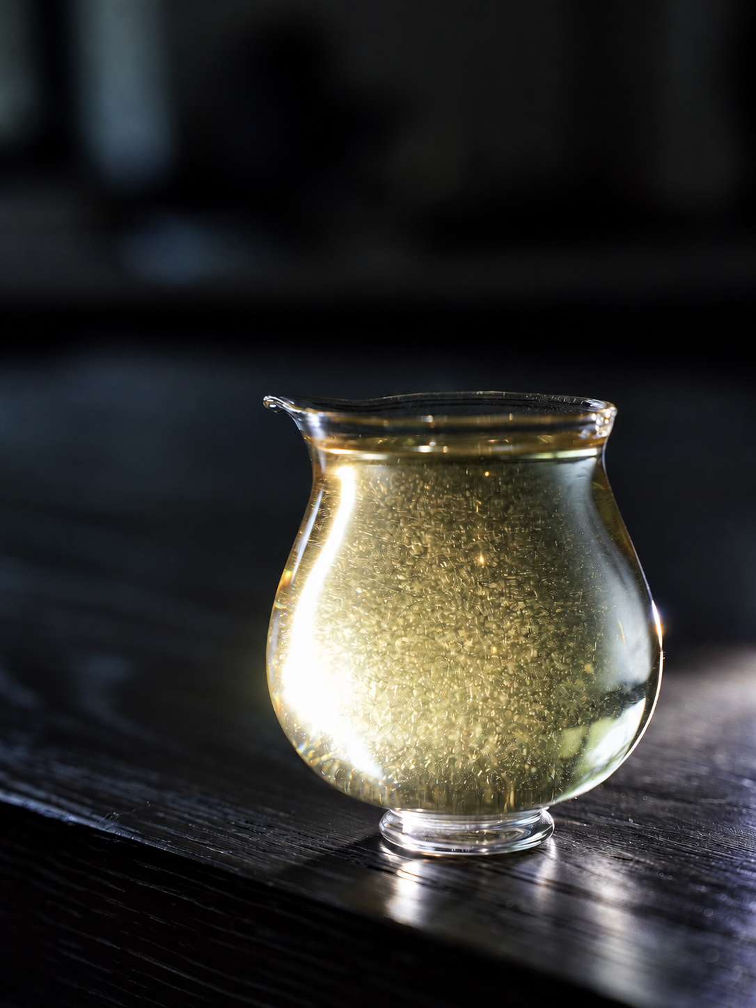 Pale yellow tea in a clear glass pitcher on a dark table