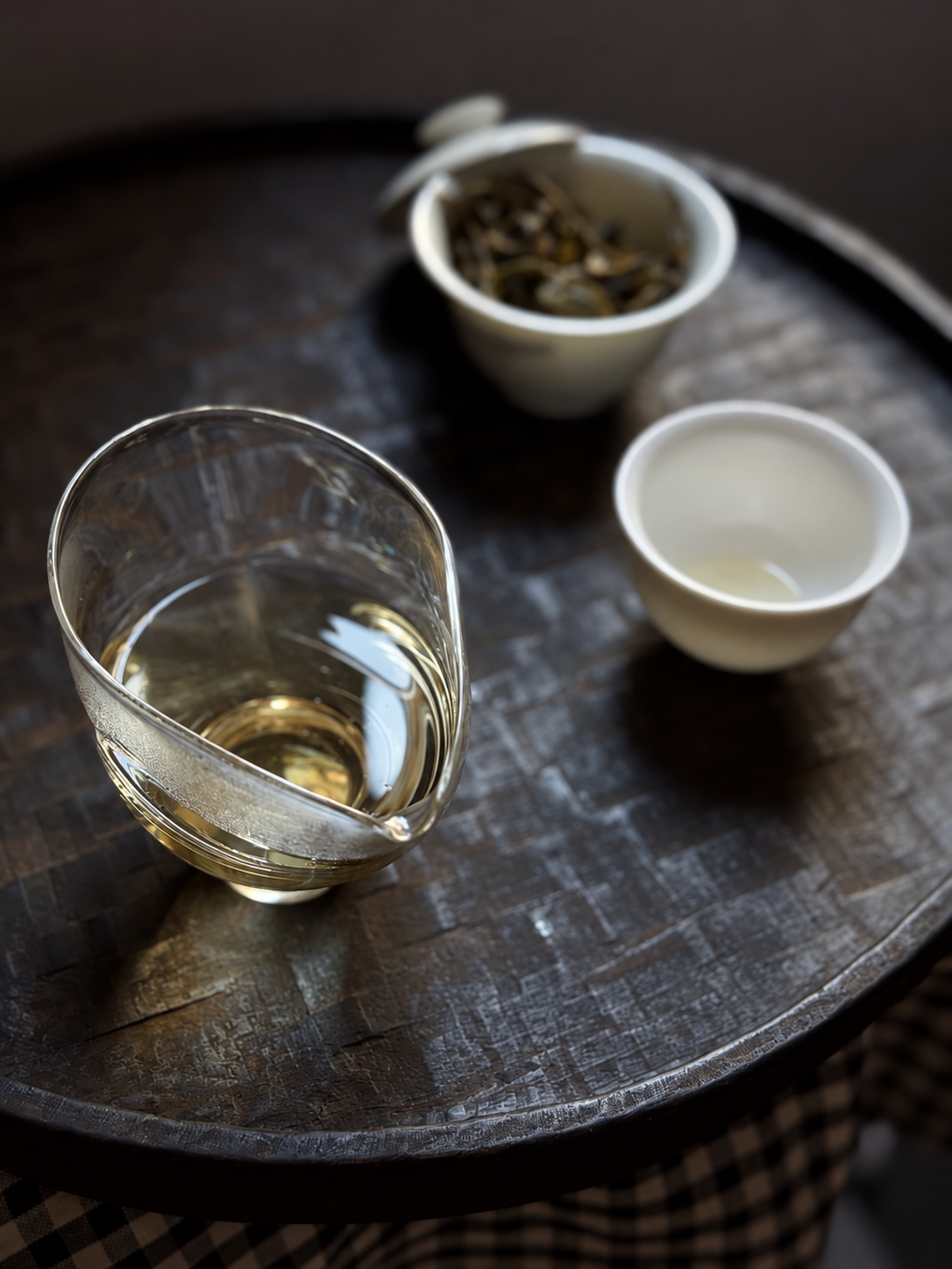 Glass pitcher, white cup and gaiwan arranged on a wooden tray