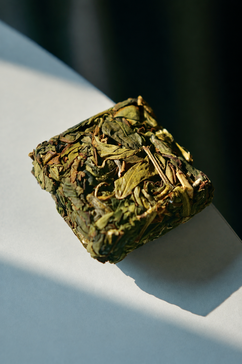 A compact square of pressed tea on a pale surface