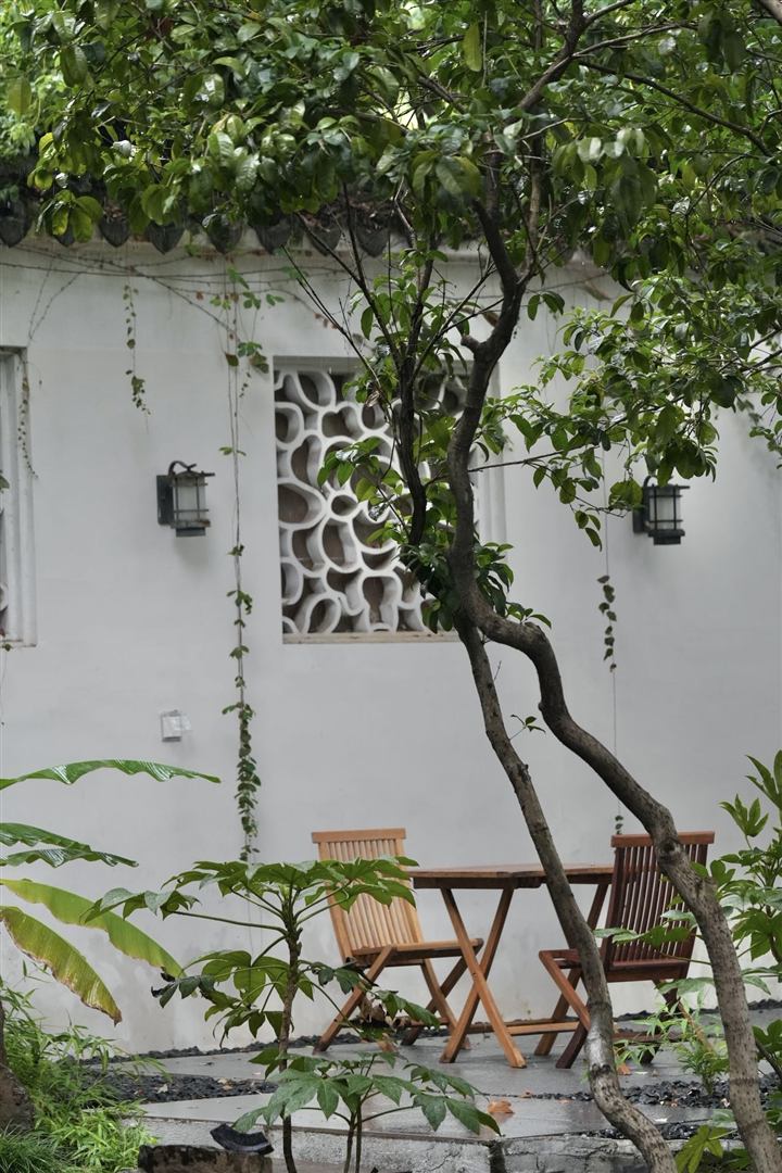 A table and chairs beside a white garden wall.